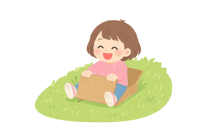 ダンボールで土手を滑り降りて遊ぶ女の子のイラスト｜外遊びの楽しさを描いた無料素材（透過PNG・商用OK）
